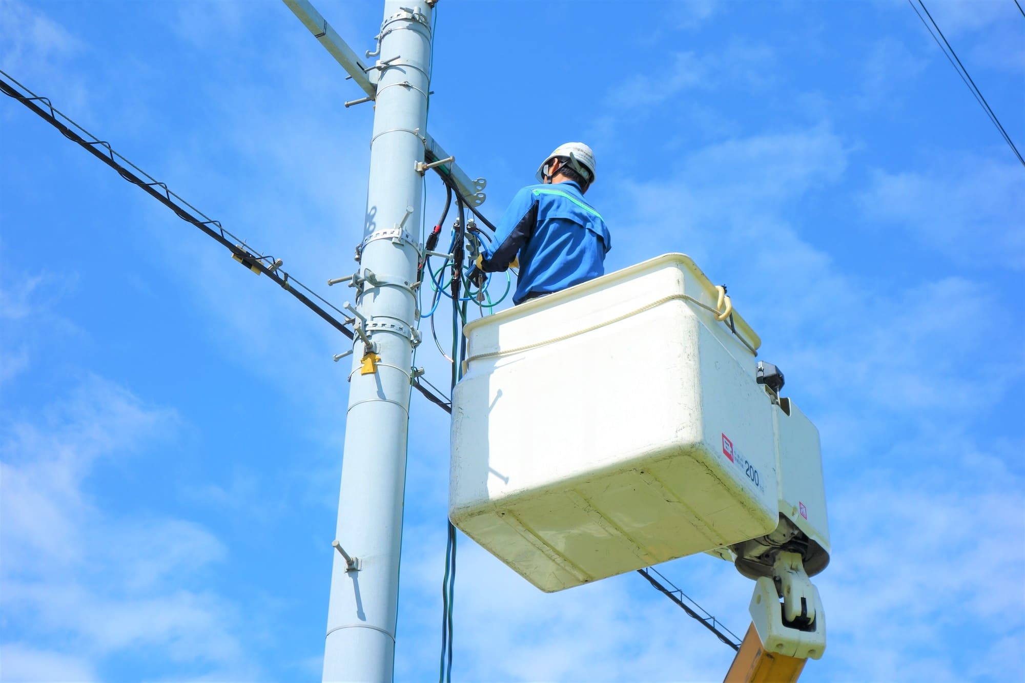 リフトに乗り電線の調整をしている作業員